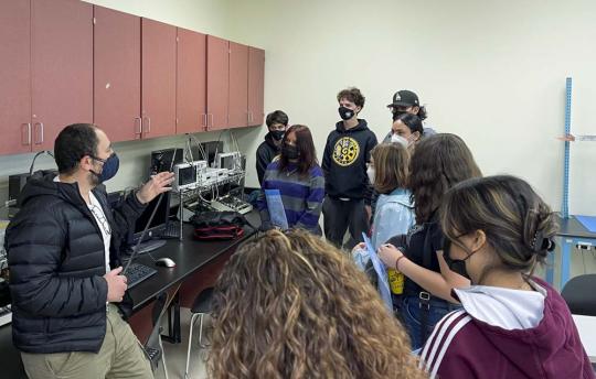 Picture of a group of high school students watching an amateur radio demonstration from engineering professor Dr. Mohamed Salem