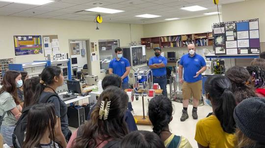 Picture of engineering students Bryce Jensen, Jason Knight-Han, and Jesus Perez giving a demonstration of the Lunabotics Rover to a group of middle school students